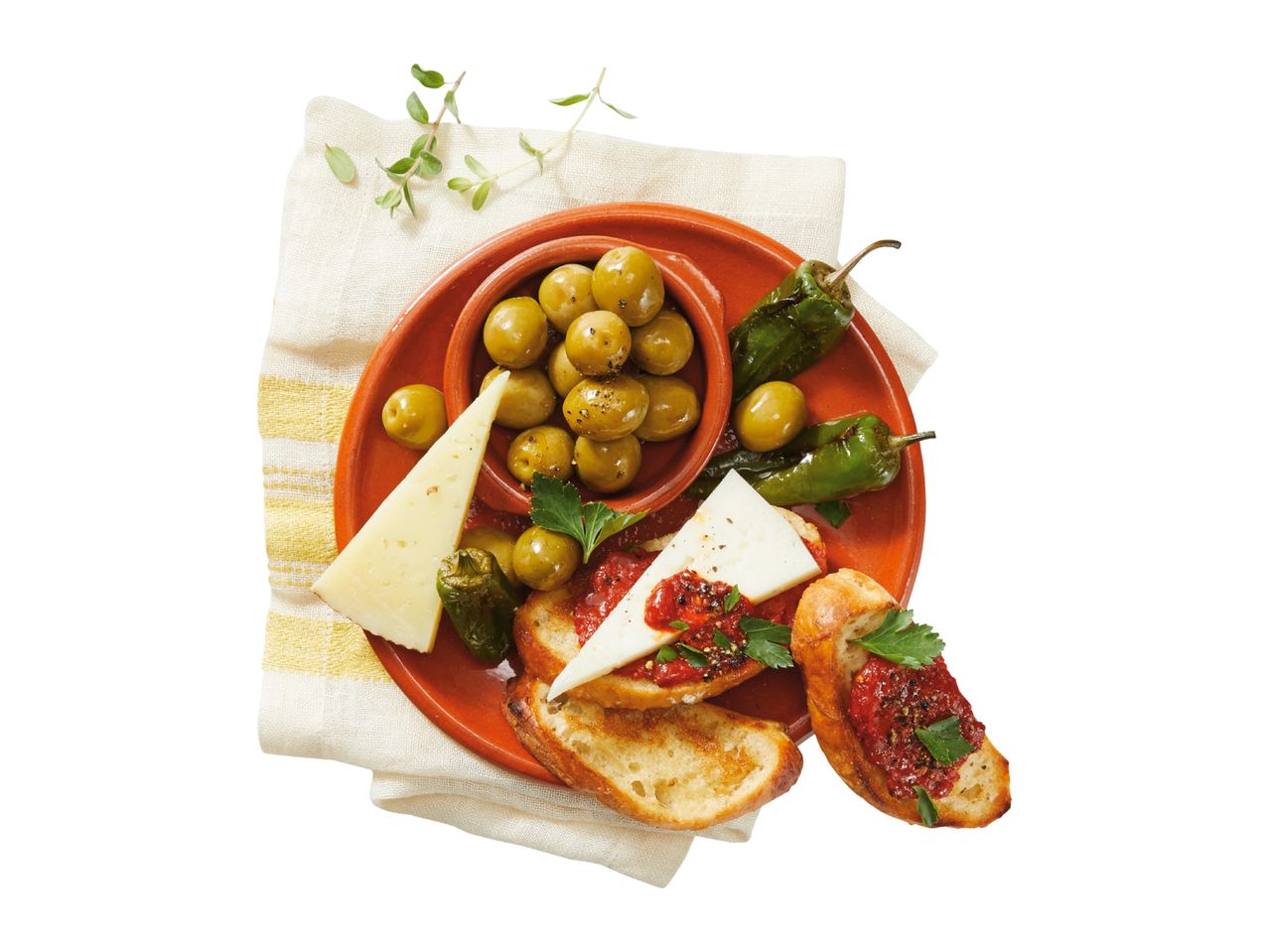 Tapas platter with green olives, cheese, roasted peppers, and bruschetta on a white background.