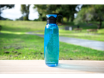 Sistema blue drinks bottle on a wooden surface with a blurred green park in the background.
