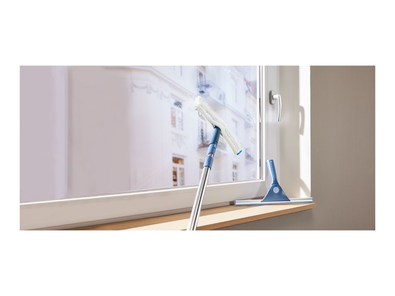 Window cleaner with telescopic handle and squeegee cleaning a window with suds.