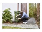 Man collecting rainwater from a green rain barrel with a downspout connection.