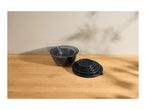 Stackable dark grey mixing bowls and lids on a wooden surface with plant shadows.