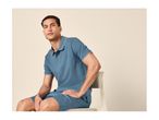 Man in a blue polo shirt and matching shorts, sitting on a chair.