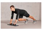 Man exercising with push-up bars and athletic shoes.
