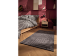 A bedroom with a patterned duvet cover, a grey rug, and a wooden nightstand.