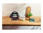 Lunch bag with food containers filled with fruit, cookies, and vegetables on a wooden counter.