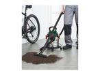 Person vacuuming dirt from the floor next to a bicycle