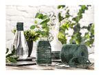 Green jute twine roll next to decorated glass vases with plants on a wooden table