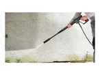 Person cleaning a textured wall with a pressure washer, removing dirt and grime.