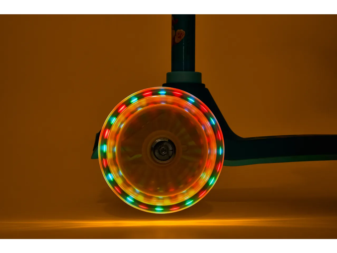 Lupilu Tri-Scooter with a spinning LED wheel, casting colorful light on a brown background.