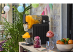 Aparat de granita care toarnă granita de portocale într-un pahar, cu alte granita și fructe.