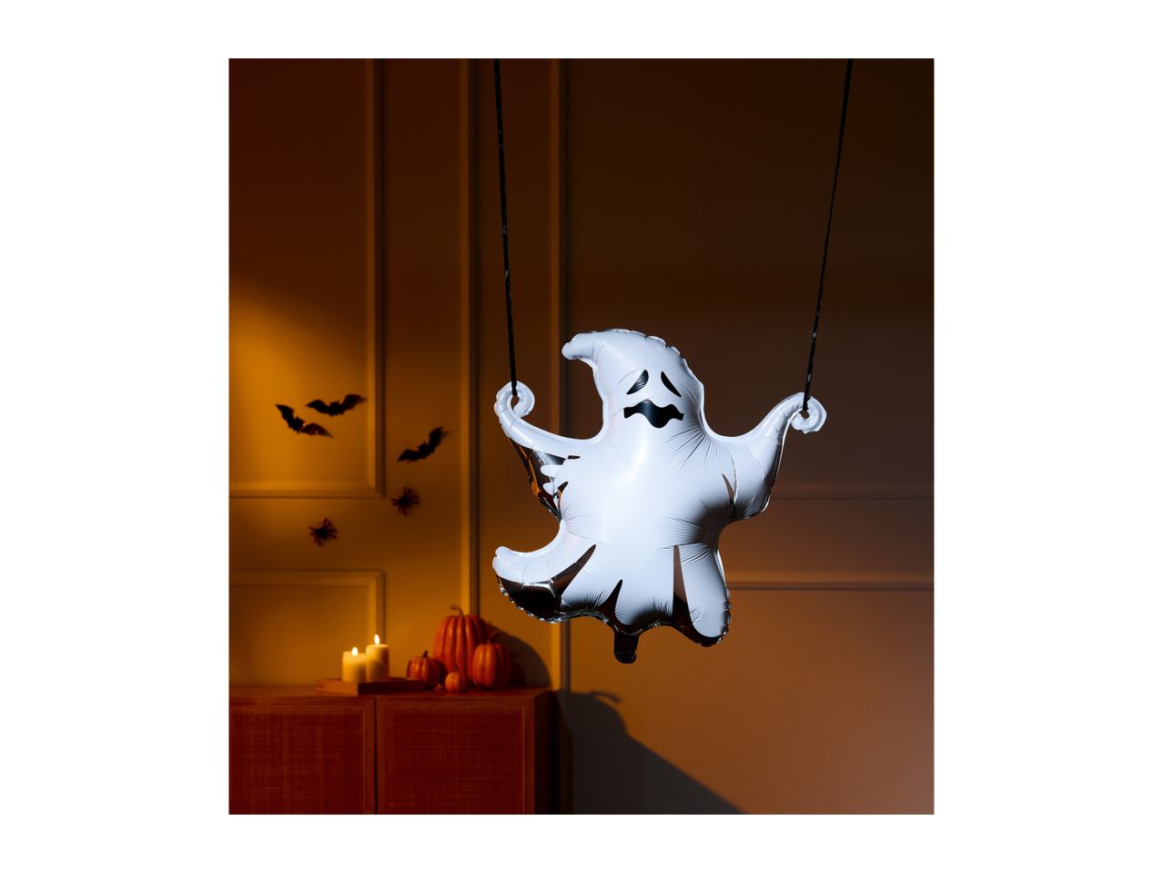 A ghost balloon and Halloween decorations, including bats, spiders, pumpkins, and candles.