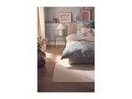 Bedroom with floral duvet cover, beige throw, and decorative elements.