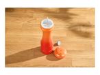 Orange pepper mill with its lid and a small cap on a wooden surface.