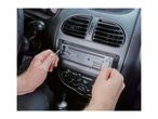 Hands removing a car radio from the dashboard of a vehicle.