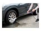 Person using a pressure washer to clean a dirty car wheel.