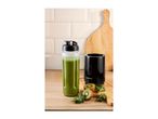 Personal blender with a green smoothie, kiwi, and kale on a wooden board.
