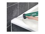 Hand applying sealant to a white bathtub edge against dark tiled wall.