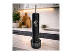 Black beverage dispenser on a marble kitchen counter with a plant and cutting boards in the background.