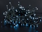 Close-up of white LED Christmas lights tangled on a dark surface, emitting a cool glow.