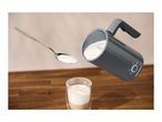 A SilverCrest milk frother pouring foam into a glass of coffee, with a spoon of foam.