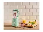 Mint green blender with berries and yogurt, fresh fruit, and orange juice on a wooden counter.