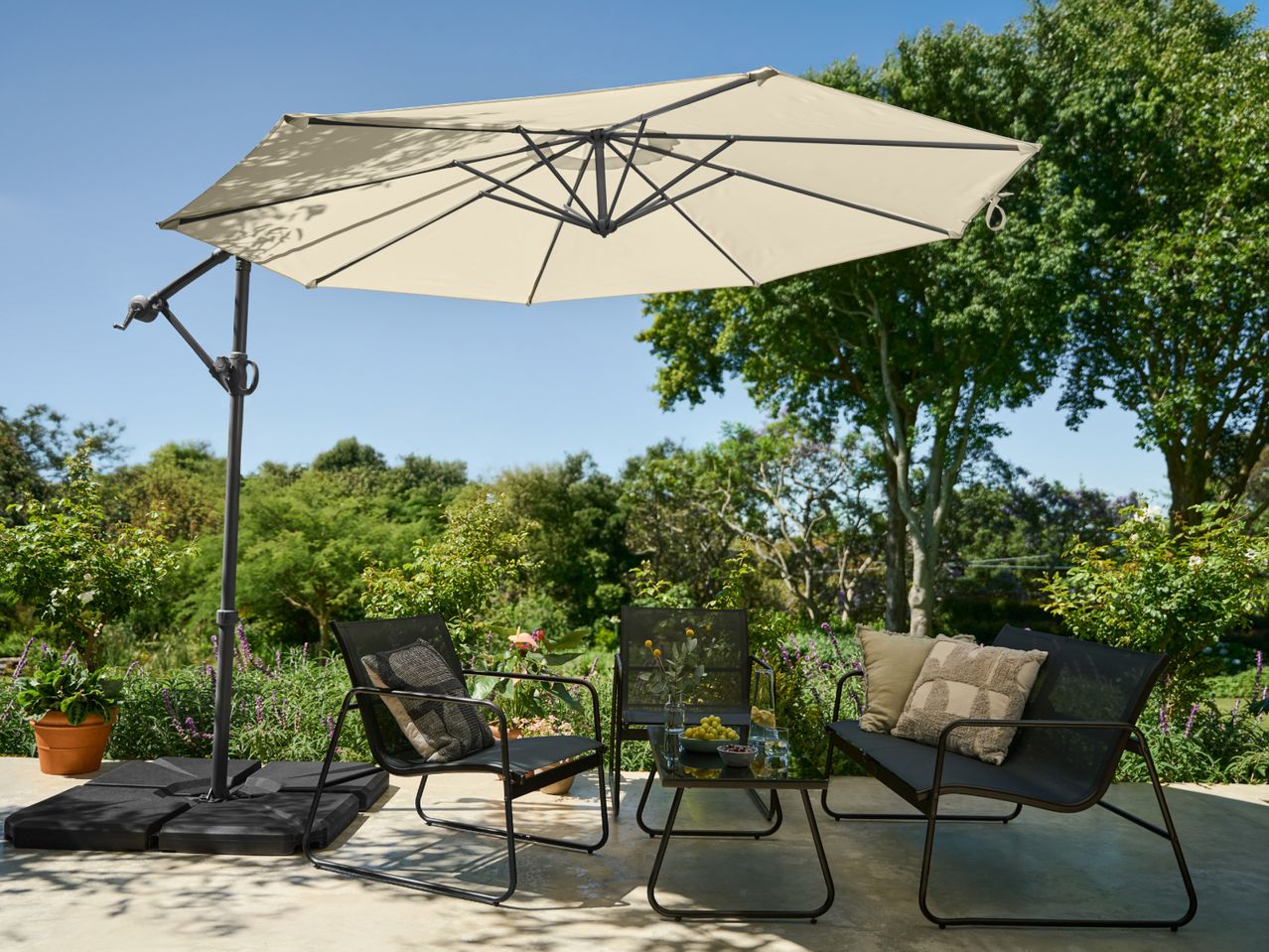 Patio umbrella with outdoor seating set, including chairs, a bench, and a coffee table.