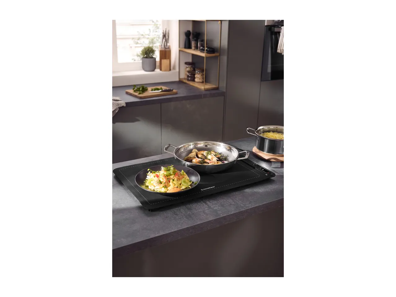 Cooked pasta and shrimp in pans on a kitchen counter with a window in the background.