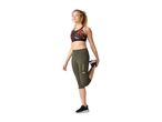 Woman in a patterned sports bra and olive green capri leggings stretching her leg.