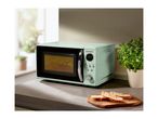 A retro-style SilverCrest microwave oven in light green on a kitchen counter with bread slices.