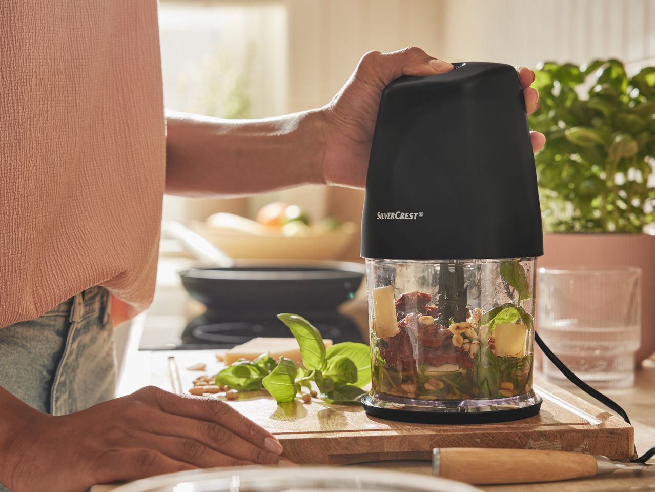 Човек използва мултифункционален чопър Silvercrest® Kitchen Tools за приготвяне на песто в кухнята.