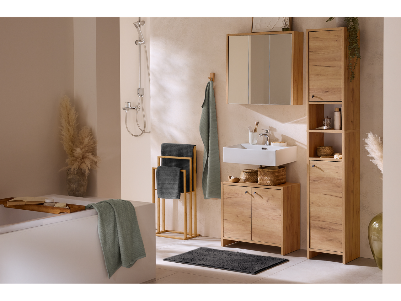 Tapete de banho Livarno cinzento escuro num chão claro com móveis em tons de madeira.