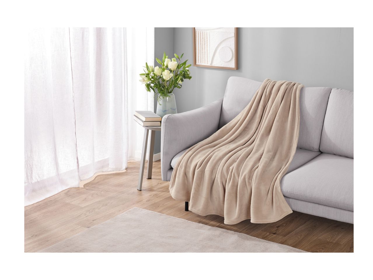 A light grey sofa with a beige throw blanket in a living room setting.