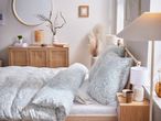 Bedroom with light blue floral bedding, wooden furniture, and decorative accents.