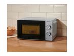 Silver microwave oven with two dials on a wooden countertop next to a bowl of bread.