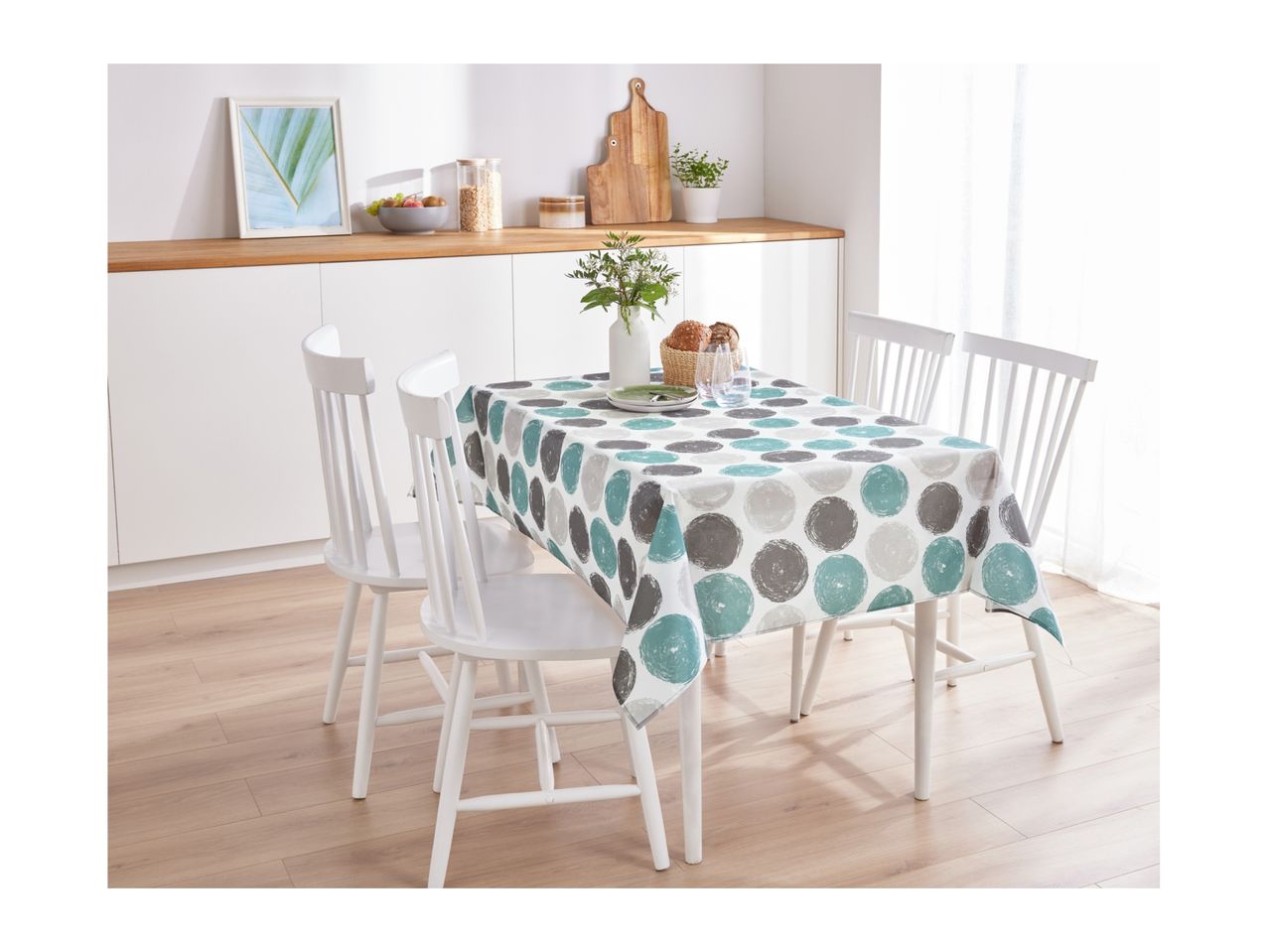 A kitchen dining area with a white table and chairs, featuring a polka dot tablecloth.