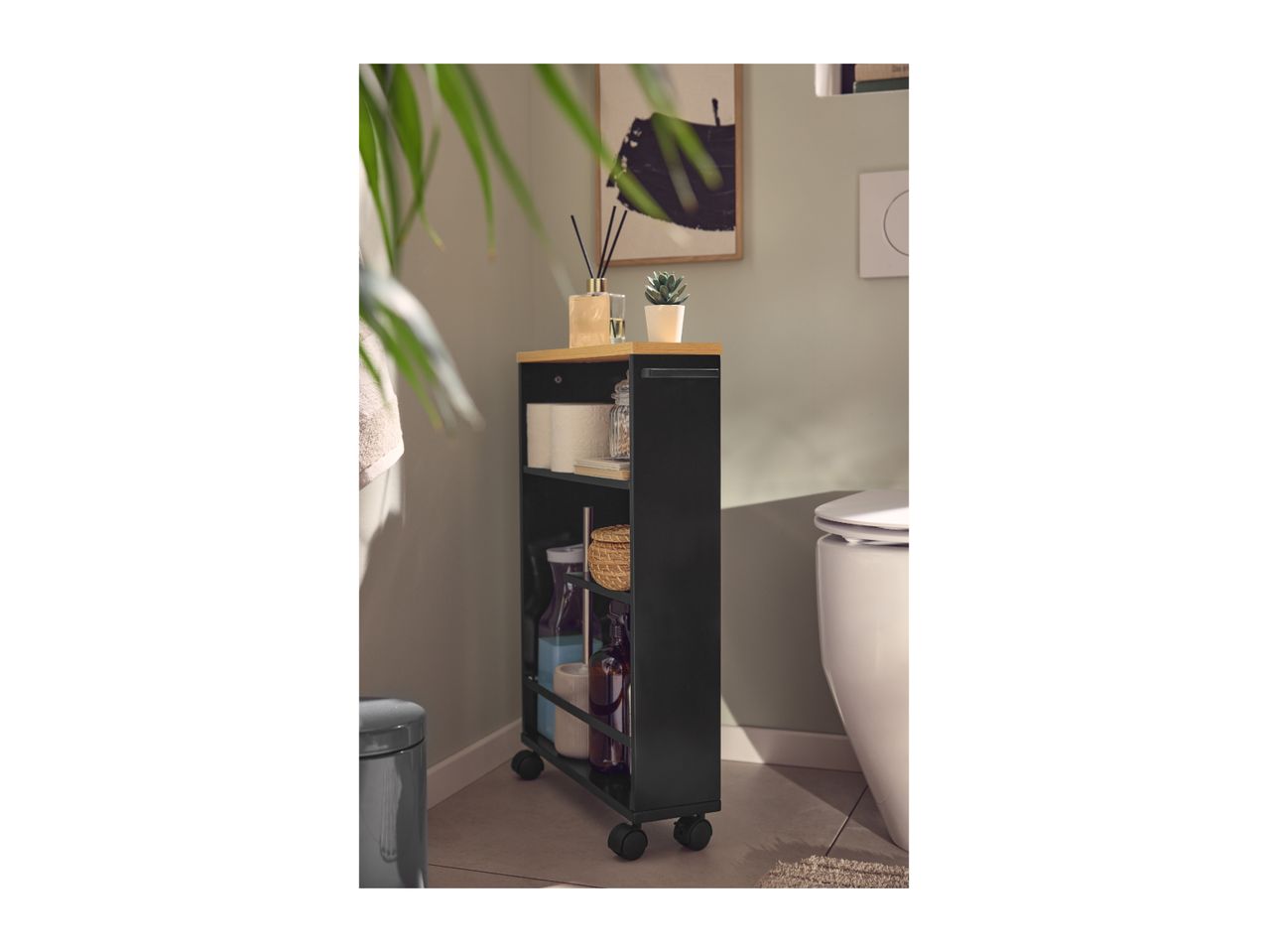 Black bathroom storage trolley with wooden top, holding toiletries and a plant, next to a toilet.
