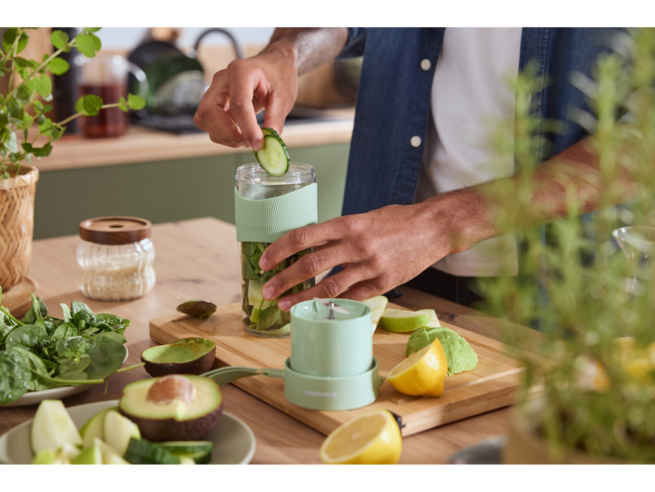 Bărbat prepară smoothie cu blenderul Silvercrest®, adăugând castravete în sticlă.