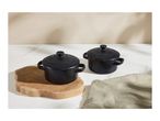 Two black mini casserole dishes on a wooden board with a linen cloth.