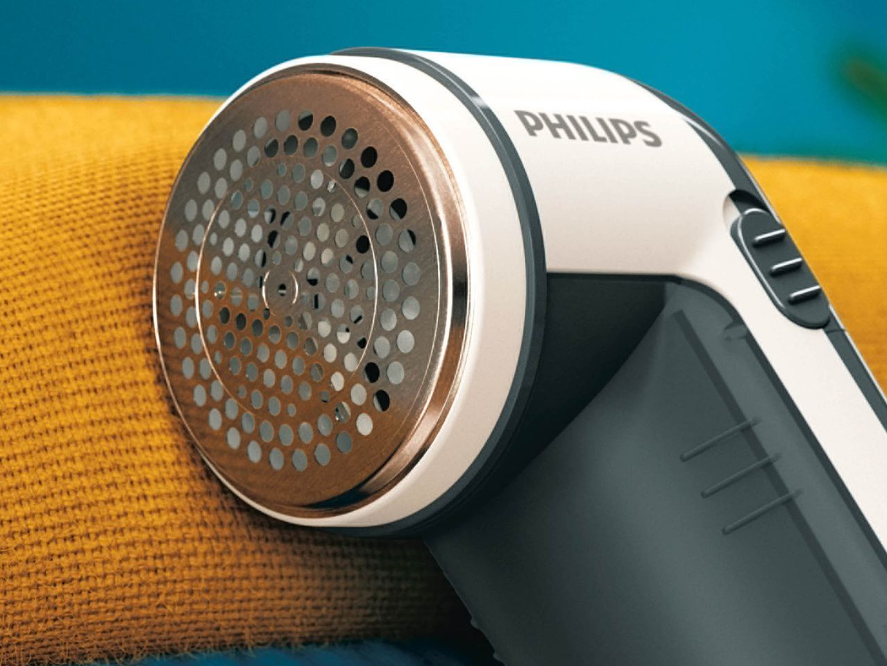 Philips fabric shaver on a yellow textile surface.