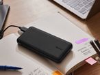 Μαύρο power bank Tronic που φορτίζει ένα smartphone, πάνω σε ένα σημειωματάριο με στυλό.
