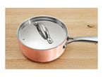 Copper saucepan with a stainless steel lid and handle on a wooden surface.