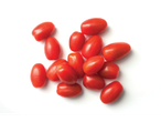 Tomates vermelhos maduros e frescos espalhados sobre fundo branco.