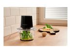 Food chopper with basil and oil, next to a cutting board with cheese and pine nuts.