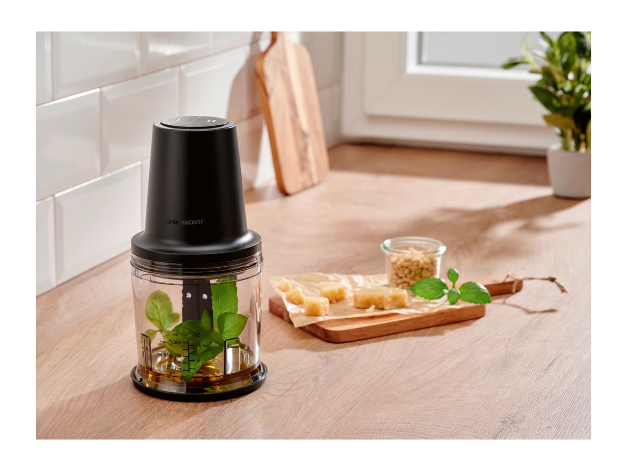 SilverCrest food chopper with basil and oil, next to cheese, pine nuts, and mint.