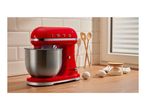 Red retro stand mixer with a stainless steel bowl on a wooden kitchen countertop