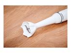 White immersion blender with a metal blade on a wooden surface.