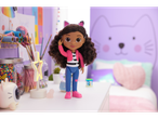 Gabby's Dollhouse doll with cat ears, pink jacket, and blue pants in a craft room.