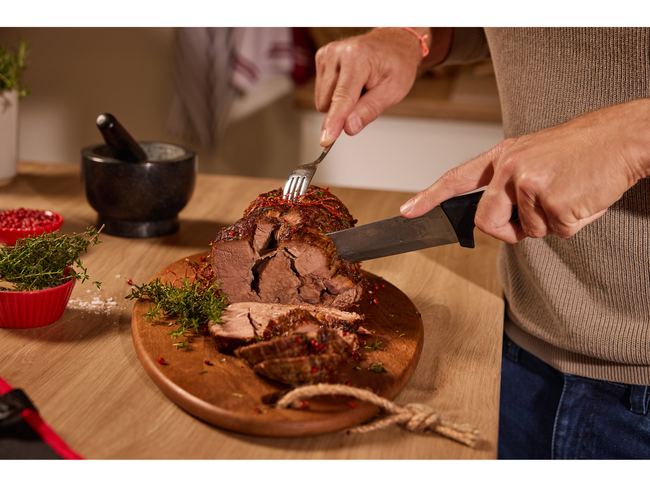 Homem a cortar um assado de carne com uma faca SilverCrest®