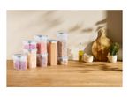 A set of clear plastic food storage containers filled with various dry goods on a wooden countertop.