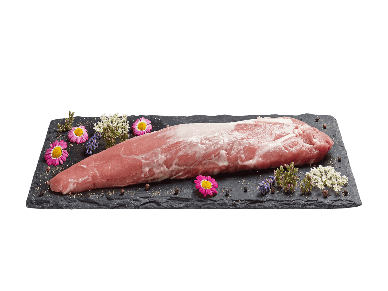 Filet de porc cru sur une assiette en ardoise noire avec herbes et fleurs